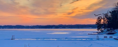orange sky, frozen lake with hockey nets and benches