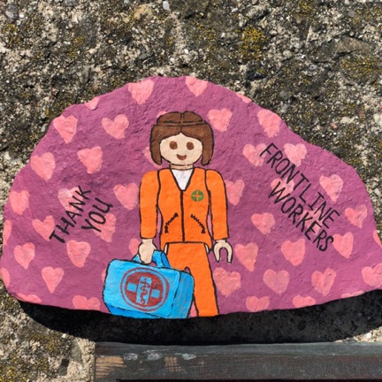 rock painted pink with pink hearts of a female medical worker dressed in orange saying thank you front line workers