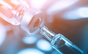 needle and syringe drawing vaccine from a bottle
