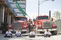 photo showing 4 people sitting on ground in front of trucks protesting