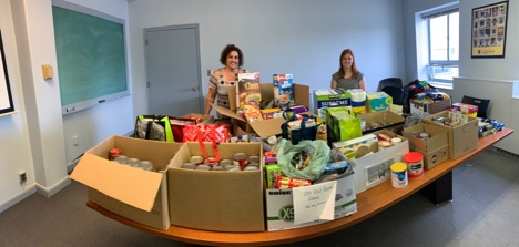 Food bank donations on table with two people standing behind