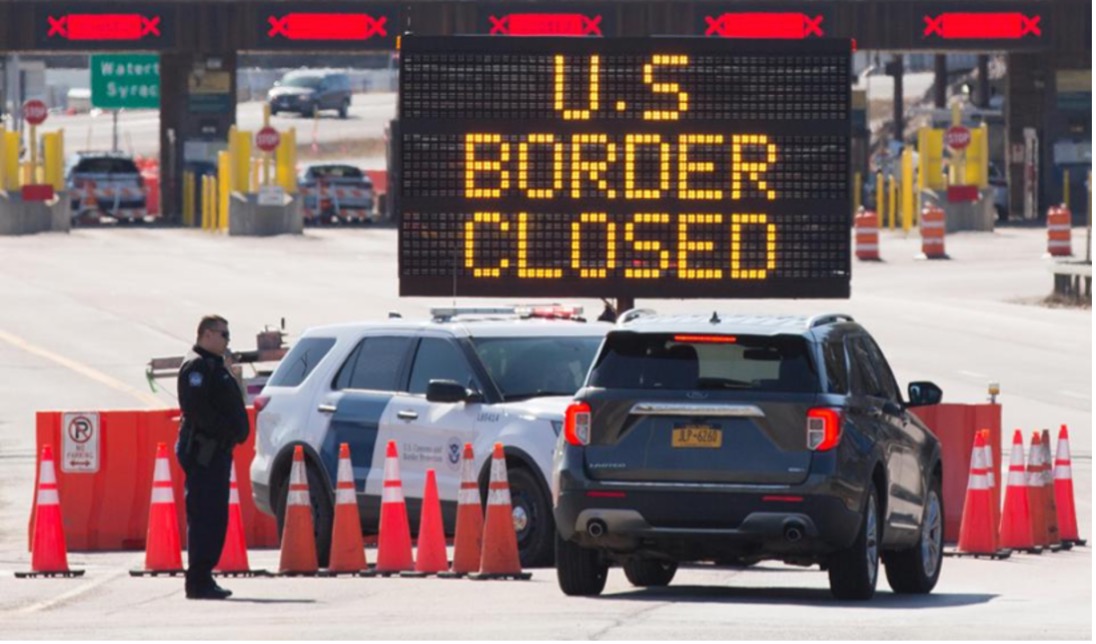 cars, piling and border officers with lit up sign saying US border closed