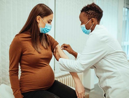 female healthcare worker administering vaccine to pregnant woman