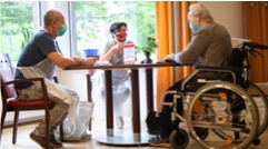 3 senior citizens sitting at a table all wearing masks