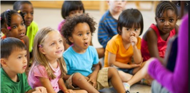 a group of young children sitting on the floor of a classroom