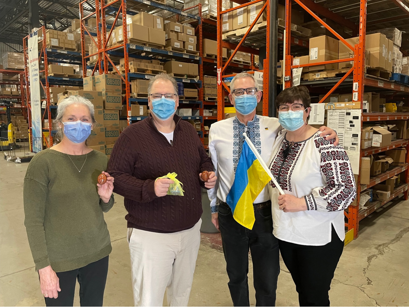 warehouse of boxes with four masked people standing in front