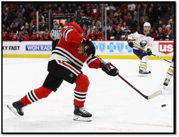 Chicago Blackhawk player taking a shot playing hockey in from of crowd