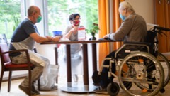 three senior citizens wearing masks sitting at a table