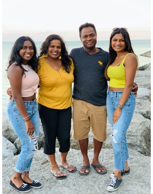 family of four posing on a rock at a beach