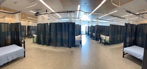 Photo of a large make shift hospital room with many beds