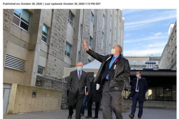 men wearing masks walking past hospital building