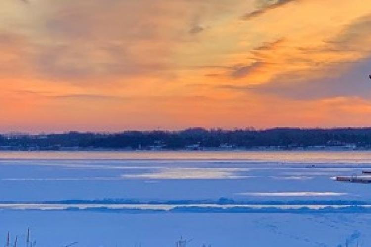 orange sky, frozen lake with hockey nets and benches