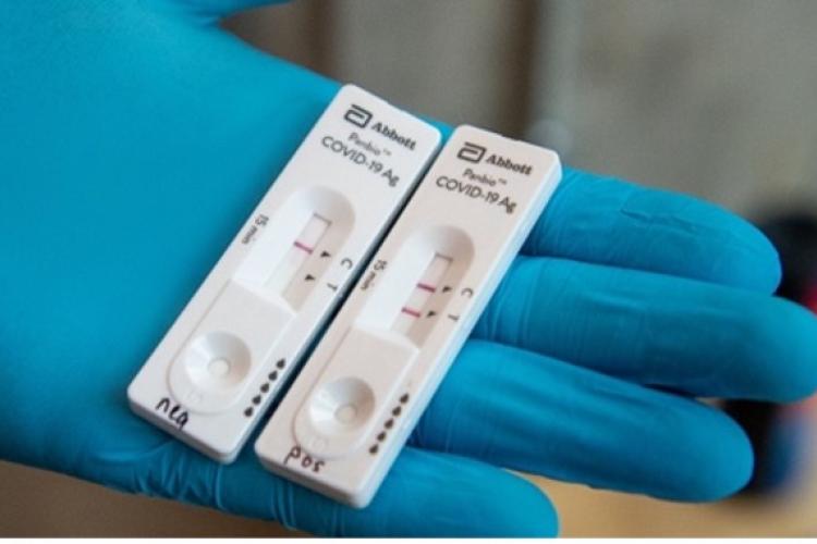 gloved hand holding 2 rapid tests