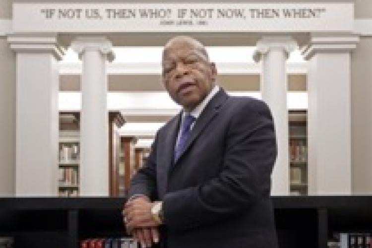 John Lewis leaning against a book case