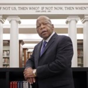 John Lewis leaning against a book case